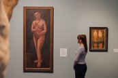 Ausstellungsansicht "Paula Modersohn-Becker und Edvard Munch. Die großen Fragen des Lebens" angeschnittene Skulptur und zwei Bilder an der Wand mit einer Besucherin