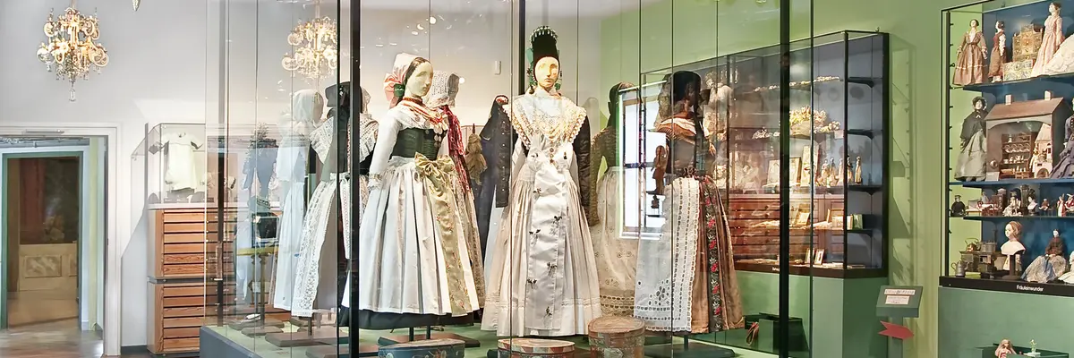 in der Mitte große Puppen in Trachten, drumherum weitere Puppen und Objekte