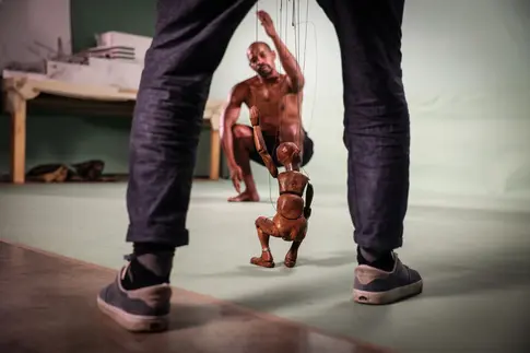 Holzpuppe zwischen den Beinen eines Menschen