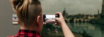 Eine Besucherin fotografiert ein Gemälde von Bernardo Bellotto