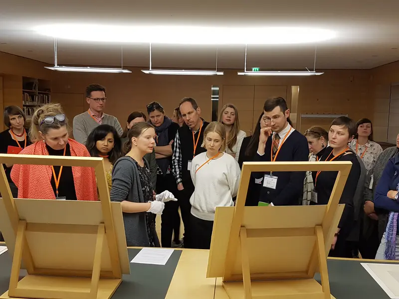 viele Personen betrachten zwei Kupferstiche, die gerade von einer Wissenschaftlerin erklärt werden