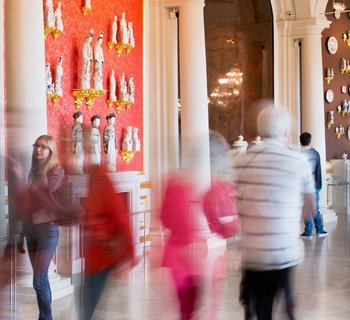 Besucher in einem Raum mit Porzellan an den Wänden und in Vitrinen