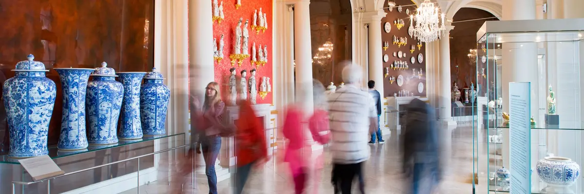 Besucher in einem Raum mit Porzellan an den Wänden und in Vitrinen