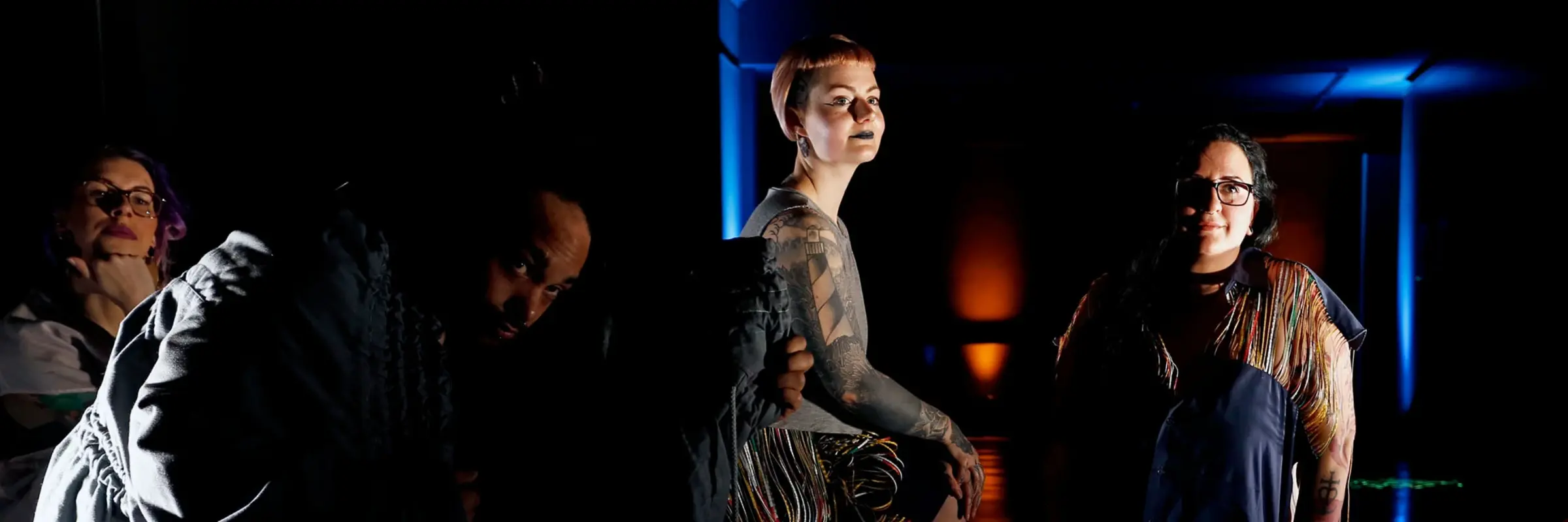 Fünf posierende Personen, beim Großteil Tattoos sichtbar