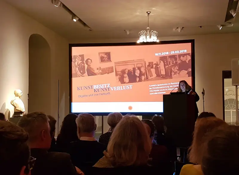 Raum mit einem großen Bildschirm zur Präsentation und sitzenden Personen