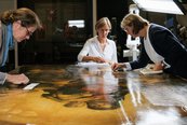 Drei Restauratorinnen arbeiten am Gemälde