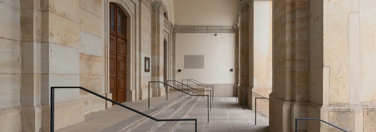 Der Eingang zu einem Gebäude mit Steinsäulen und Treppen.