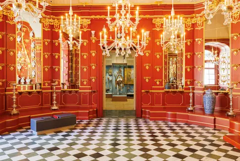 Raumansicht mit roten Wänden und goldenen Kronleuchtern