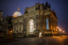 Barockes Gebäude bei Nacht mit einer der erleuchteten Kuppel im Hintergrund